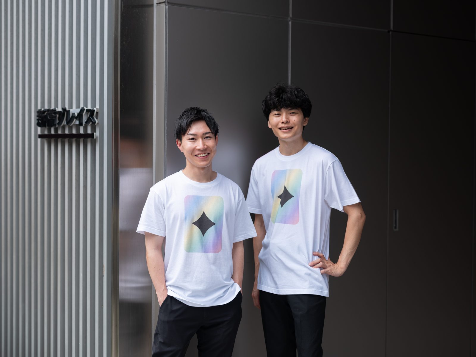 新橋オフィスの前に立つ代表・岸田佳祐（左）と取締役・甲斐響太郎（右）